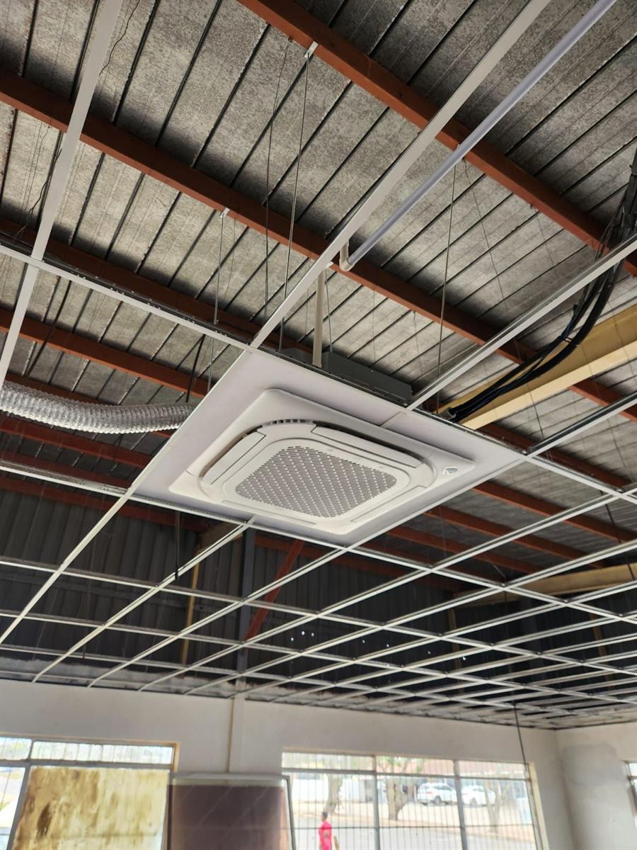 Technician installing a ducted indoor unit from scaffolding